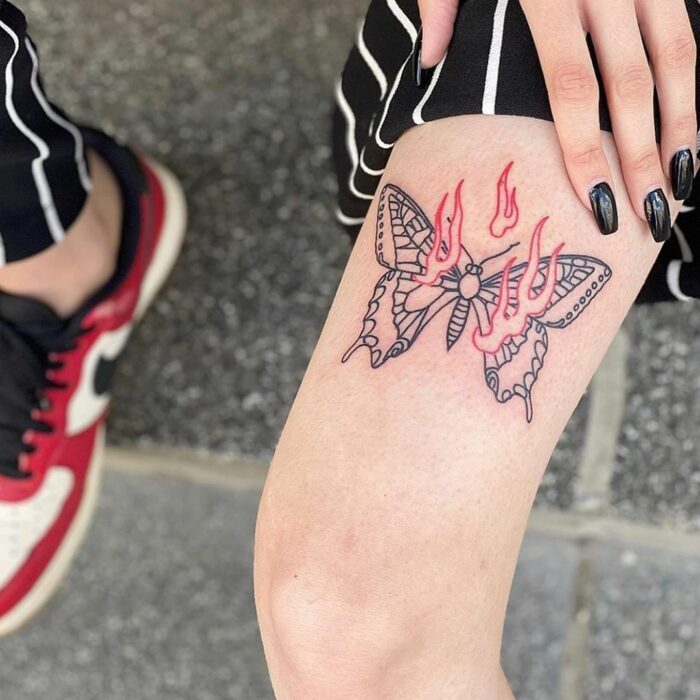 Chica con un tatuaje de color rosa en forma de mariposa con llamas 