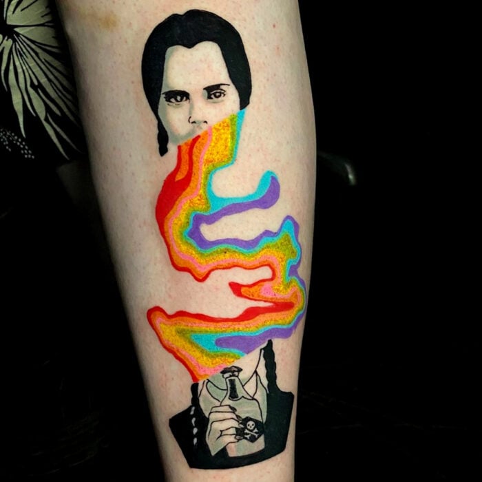 Diseños bonitos de tatuajes de Merlina Addams con arcoíris  en el brazo