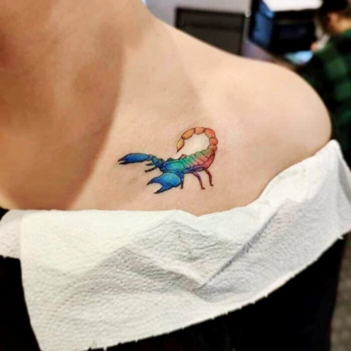 Diseños bonitos de tatuajes de escorpión de colores arcoíris en la clavícula