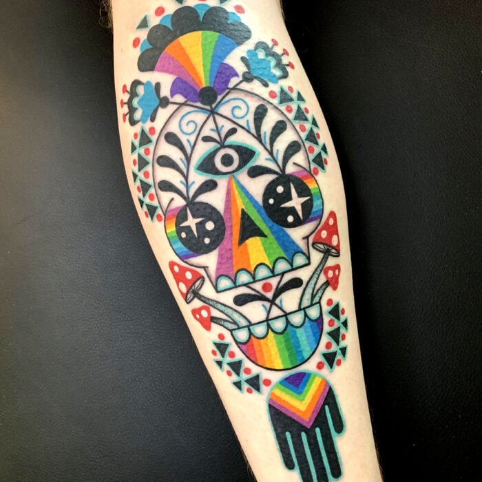 Diseños bonitos de tatuajes de arcoíris y calavera en el brazo