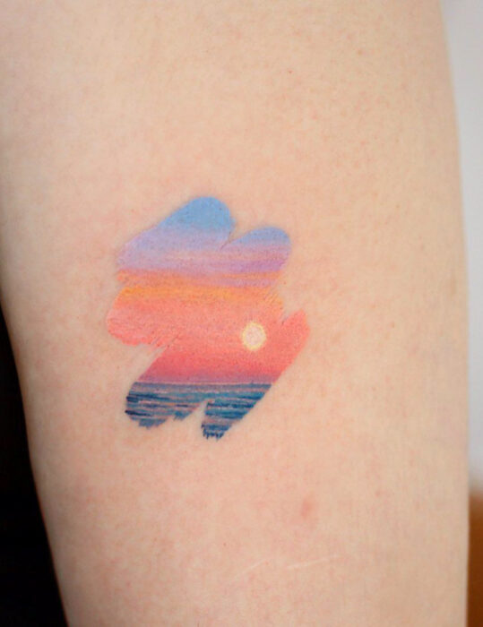 Diseños de tatuajes originales; tatuaje en el brazo de pincelada con paisaje de atardecer en la playa