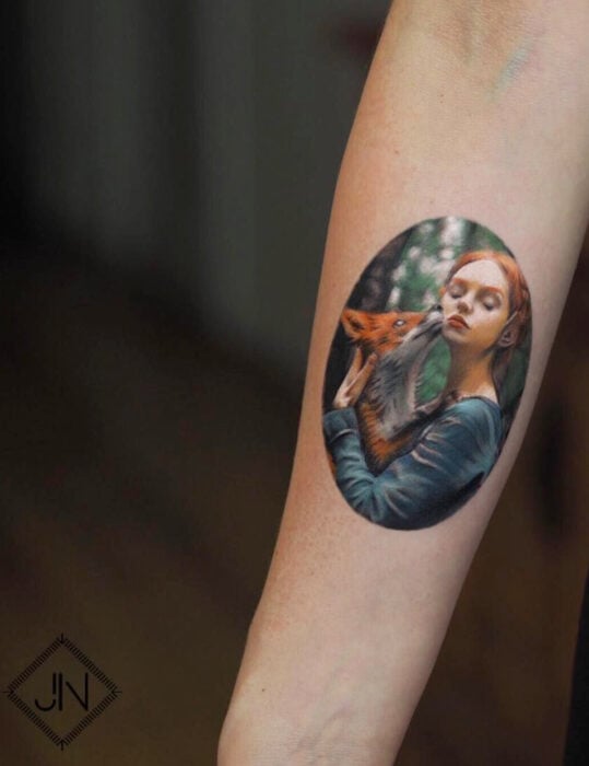Diseños de tatuajes originales; fotografía de mujer pelirroja con zorro en el bosque, tatuaje realista en el brazo