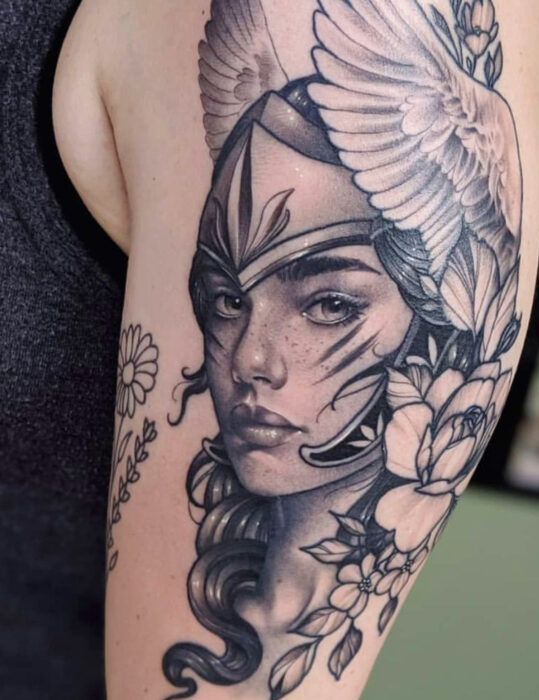 Diseños de tatuajes originales; tatuaje en blanco y negro de rostro realista de guerrera amazona en el brazo