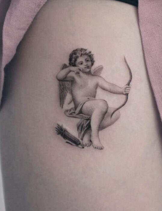 Diseños de tatuajes originales; querubín pequeño en blanco y negro, minitatuaje en el muslo