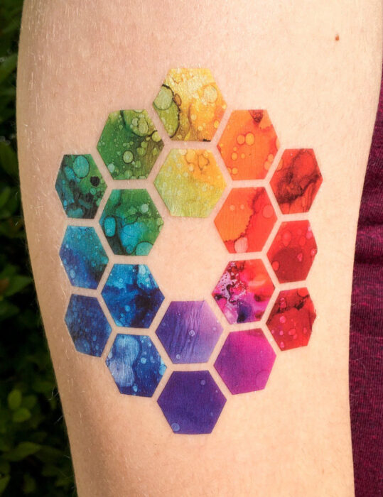 Diseños de tatuajes originales; tatuaje de círculo cromático, hexágonos de colores arcoíris; tatuaje geométrico en el brazo