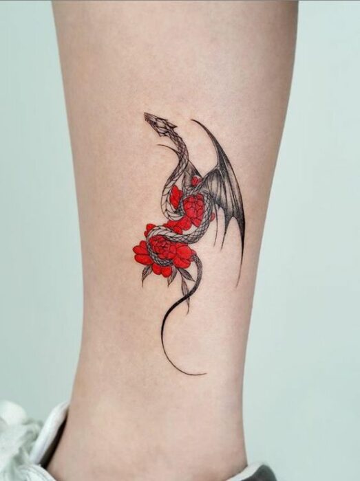 Chica con tatuaje de una dragón sosteniendo flores rojas