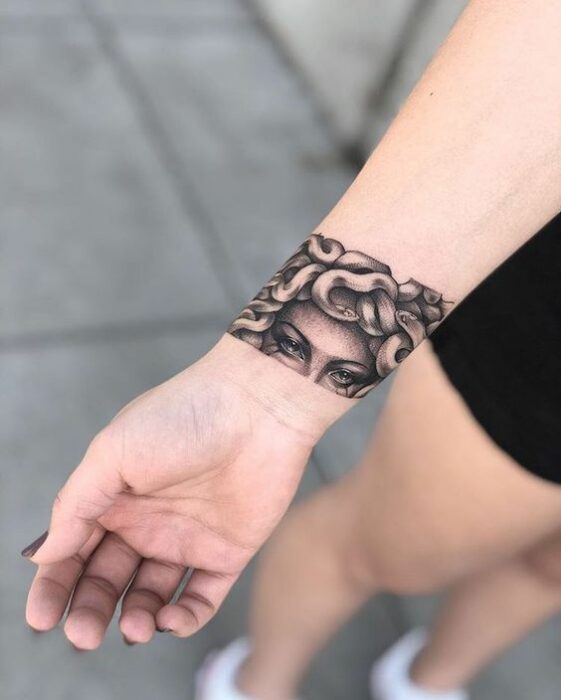 Chica con tatuaje de Medusa en forma de brazalete 