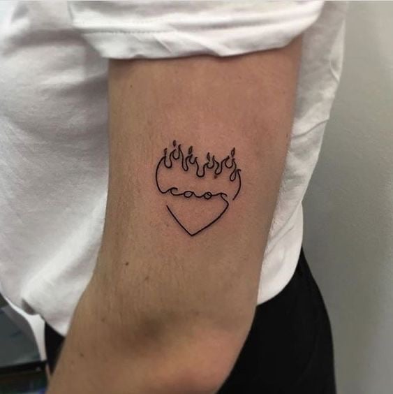 Chica con tatuaje en forma de corazón con púas en el codo  