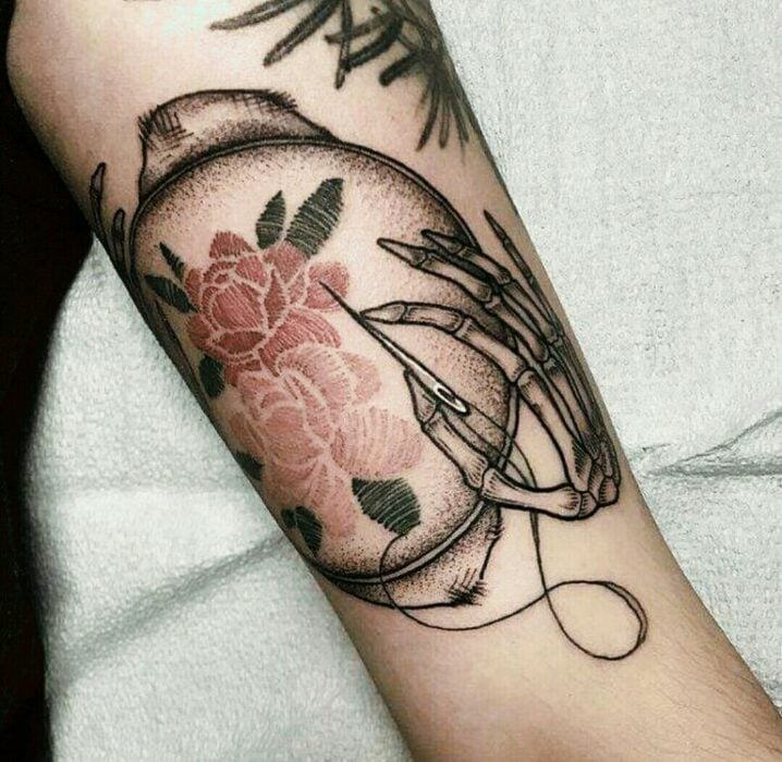 Chica con tatuaje de una mano cadavérica bordando