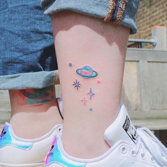 Tatuaje en el tobillo de planetas con colores fluorescentes 