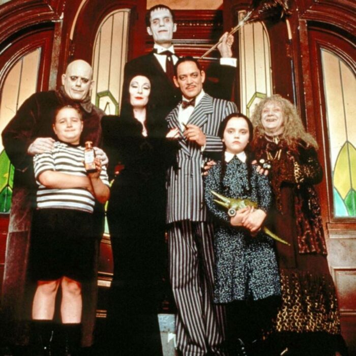 Elenco de Los locos Addams frente al pórtico de su casa 