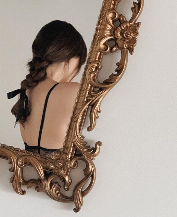 Chica con una trenza tomándose foto en el espejo