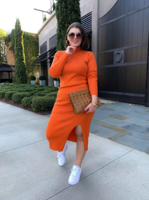 Chica curvy usando un vestido color naranja, con tenis blancos 