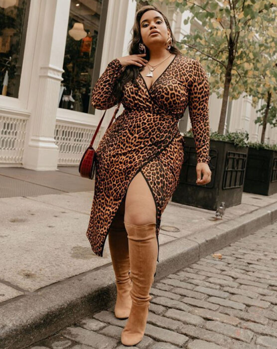 Chica curvy usando un vestido con estampado de animal print, escote en V y botas altas color camel