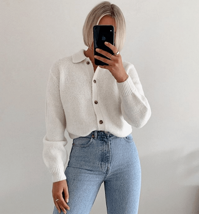 chica de cabello platinado usando un top blanco de botones con mangas largas y skinny jeans a la cintura