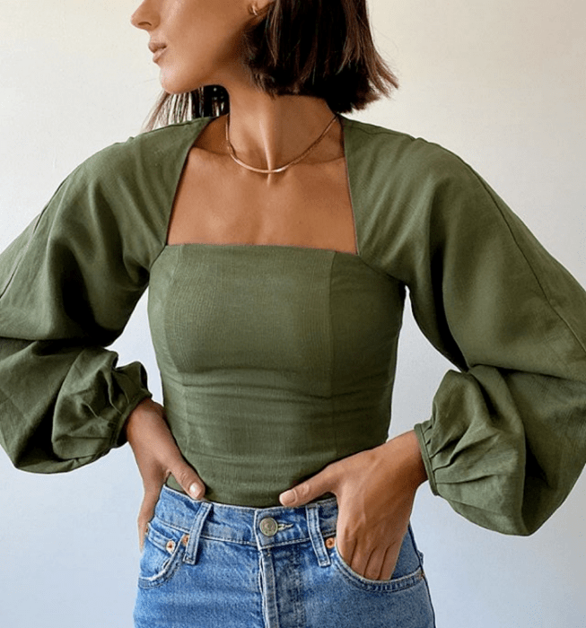 chica de cabello corto usando una blusa verde de escote cuadrado y mangas abombadas, skinny jeans