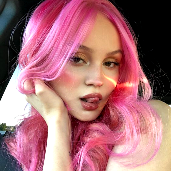 chica de cabello rosa pastel largo, con ondas y maquillaje natural