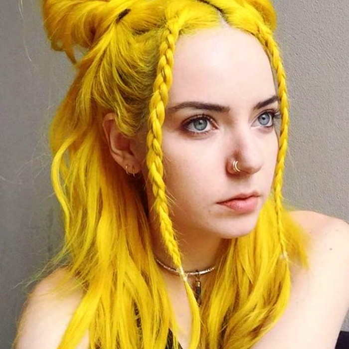 chica de cabello teñido color amarillo neon con trencitas al frente y piercing en la nariz