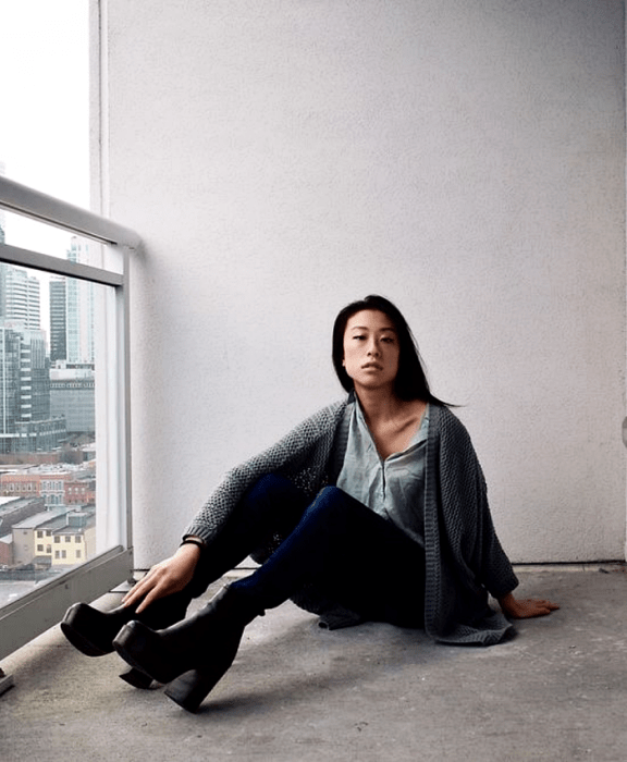 chica de cabello negro usando una camisa gris, cárdigan gris, skinny jeans y botines negros de plataforma