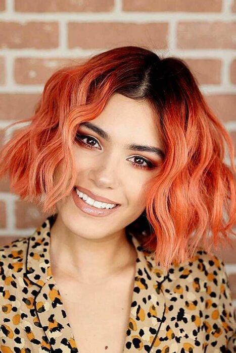 Chica con el cabello cortado hasta la barbilla y teñido en color naranja con la raíz negra 