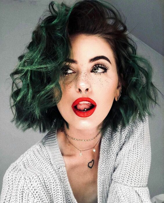 Chica con el cabello rizado y teñido de color verde menta 