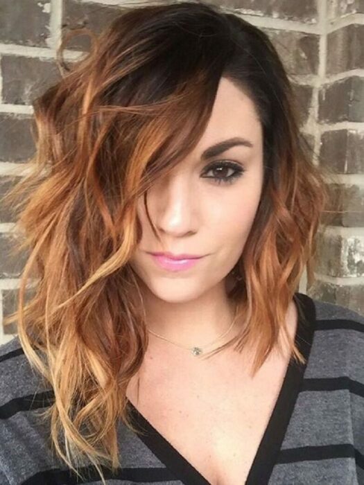 Chica con un corte asimétrico y teñido de color cobre con dorado