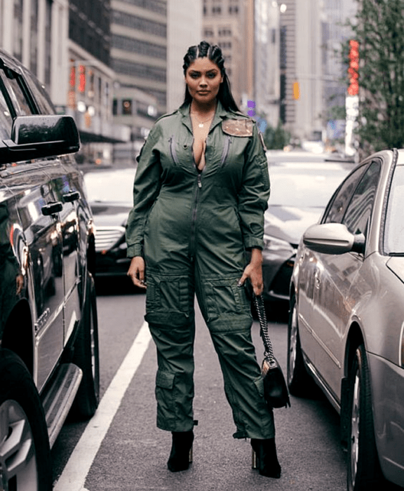 chica morena curvy usando un jumpsuit verde militar, botines negros de tacón, bolso negro de mano