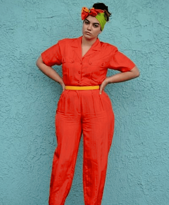 chica curvy con banda verde en el cabello, jumpsuit rojo de manga corta con cierre de botones, cinturón amarillo