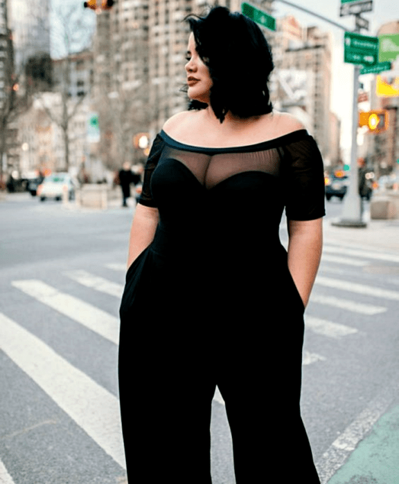 chica curvy con cabello corto usando un jumpsuit negro a los hombros con escote de corazón y pantalón largo tipo de vestir