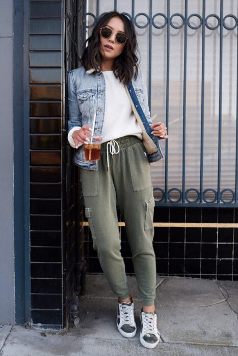 Chica usando unos pants de color verde con una camisa de color blanco y chamarra de jean