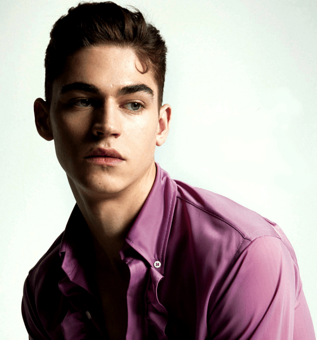 Hero Fiennes-Tiffin; chico de cabello castaño corto de ojos azules usando una camisa de vestir lila