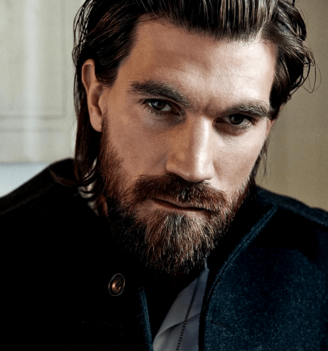 Henrik Fallenius; modelo de barba castaña con cabello largo, usando un abrigo negro