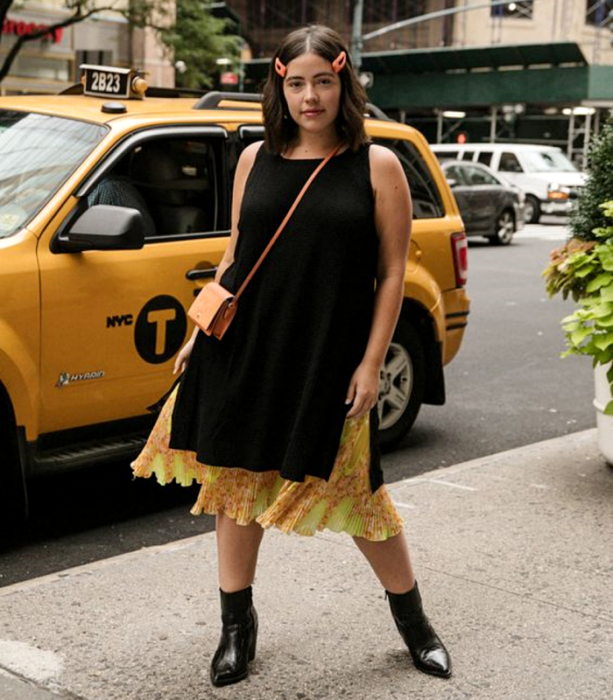 chica curvy de cabello castaño usando un vestido café con falda amarilla de flores, botines de piel cafés de tacón