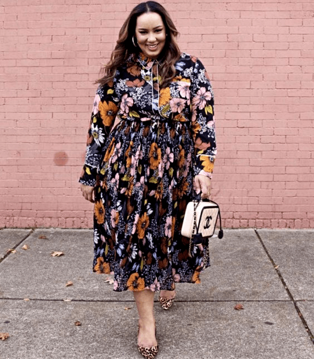 chica curvy de cabello castaño claro usando un vestido largo de flores con cuello cerrado y manga larga, bolso beige chanel y zapatos de tacón con animal print