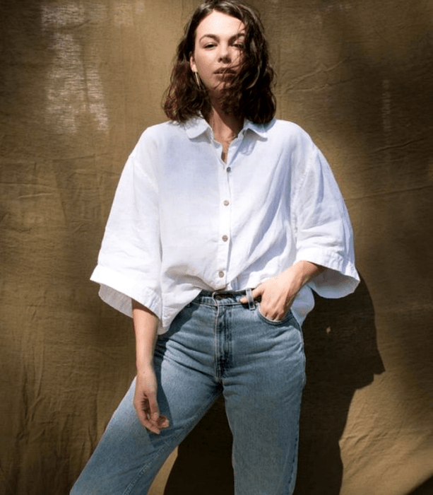 chica de cabello castaño usando una camisa oversized blanca de manga 3/4 con mom jeans a la cintura