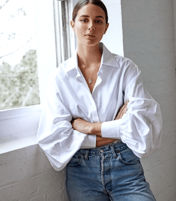 chica de cabello castaño usando una camisa oversized blanca con mangas abombadas, mom jeans a la cintura