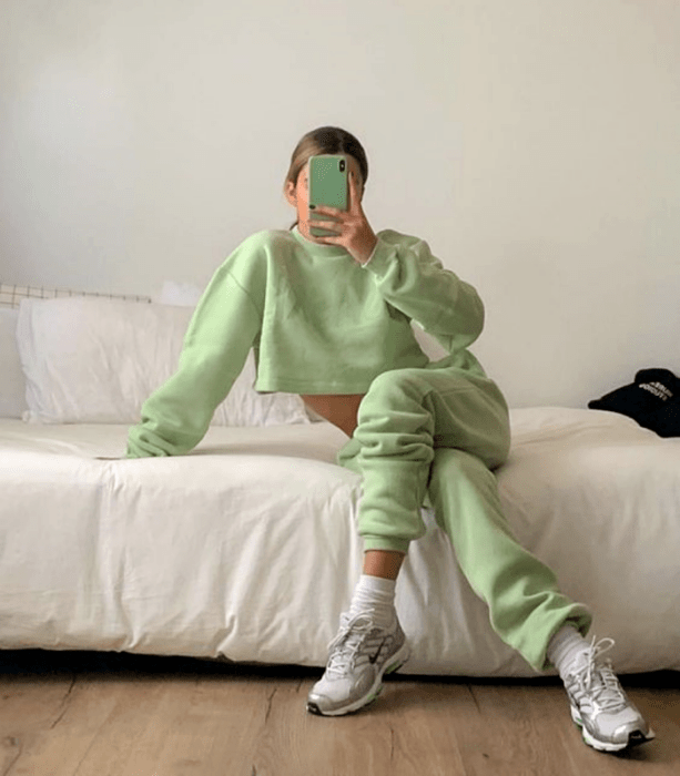 chica de cabello claro usando una sudadera verde pastel, pants verde pastel, tenis blancos