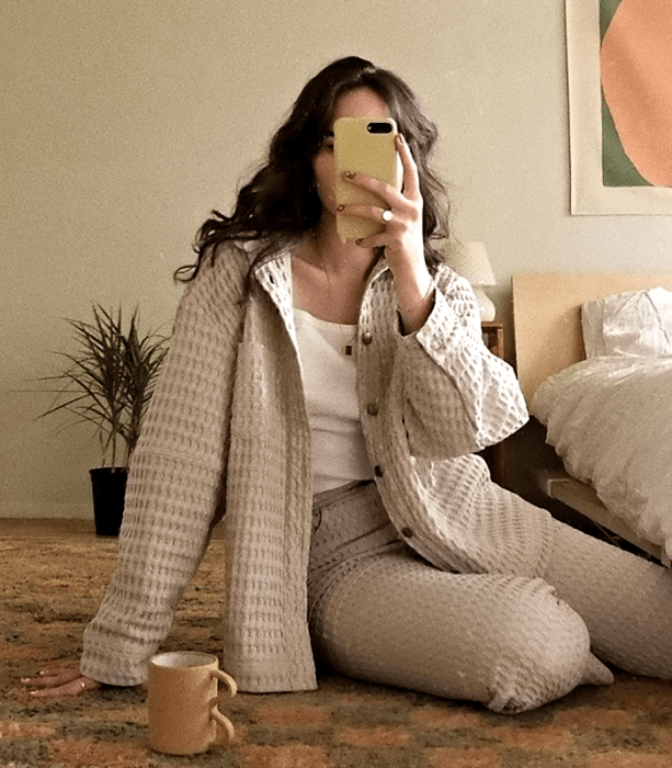 chica de cabello castaño usando un top blanco, abrigo corto beige, pantalón de vestir con textura beige