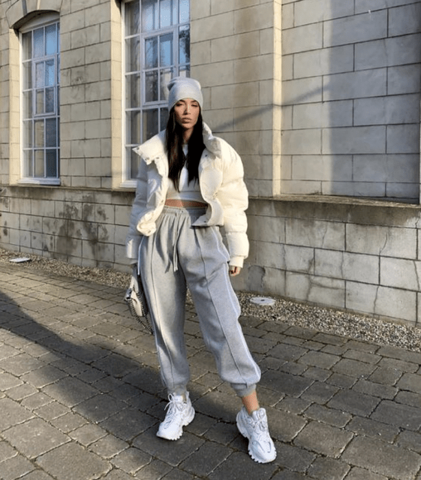 chica de cabello negro con gorro gris, top blanco, chamarra crop top blanca, pants oversized grises, tenis blancos y bolso de mano gris