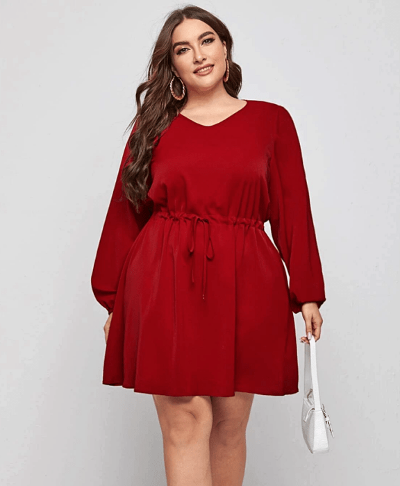 chica curvy usando un vestido rojo de cuello redondo, mangas largas, ajuste a la cintura y bolso de  mano blanco