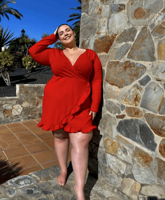 chica curvy usando un vestido rojo de manga larga, cuello en V, holanes en la falda