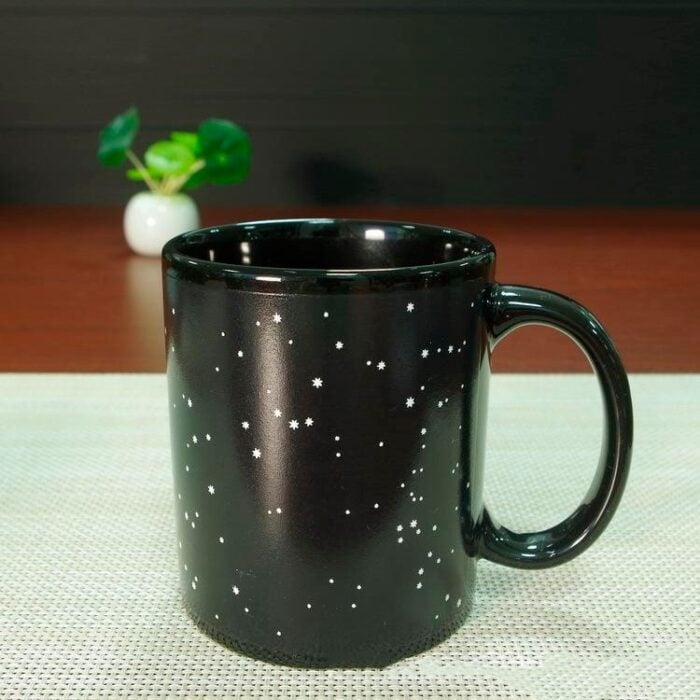 Taza de fondo negro con constelaciones en color blanco