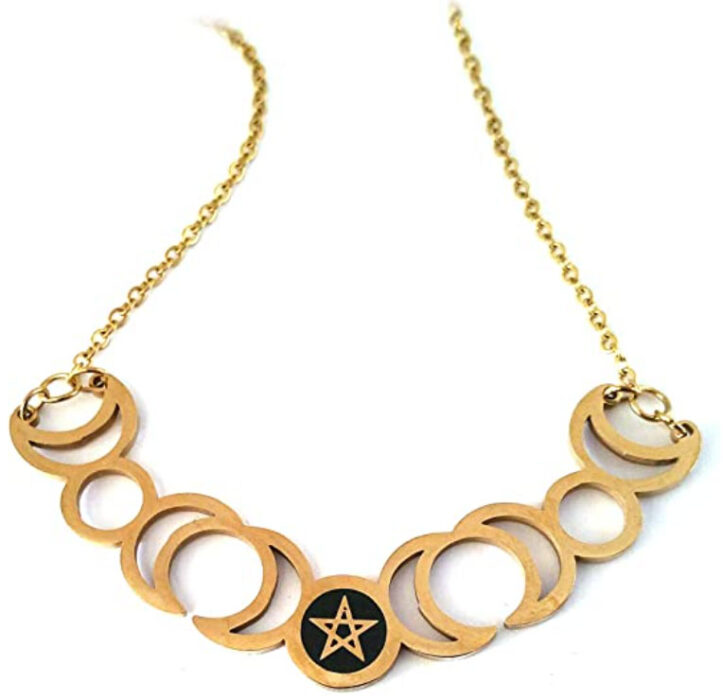 Collar en color dorado con las fases de la luna y una estrella en fondo negro en el centro