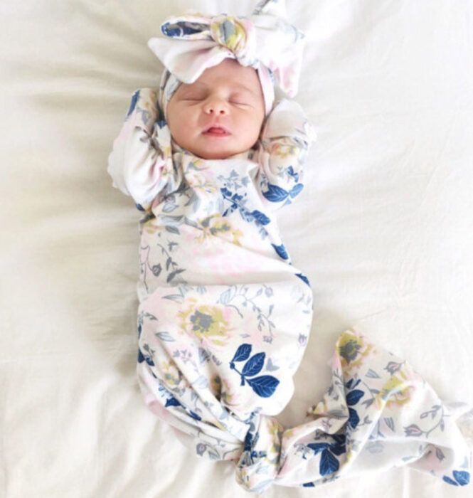 Bebé recién nacida, usando un moño blanco con azul, y un costalito de los mismos colores