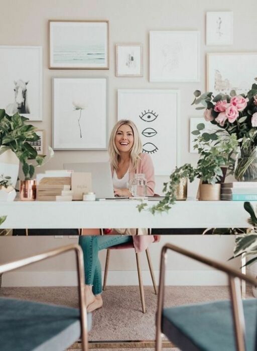 Chica trabajando en su escritorio que tiene varias macetas con plantas