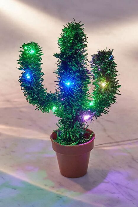 Árbol de navidad en forma de cactus pequeño en una maceta con luces azules y verdes 