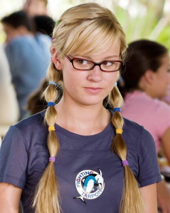 Brie Larson adolescente con blusa azul, dos colitas con ligas de colores y gafas 