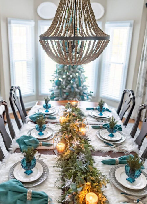 Mesa de comedor con manteles individuales blancos, platos blancos con servilletas turquesas y decoración turquesa  y camino de mesa de ramas de pino