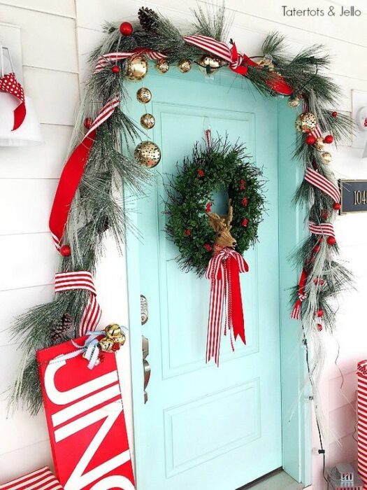 Puerta color azul Tiffany en una casa blanca con de hojas de pino y una corona con un moño rojo