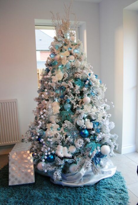 Árbol navideño blanco con esferas azules aqua y turquesa en una habitación blanca